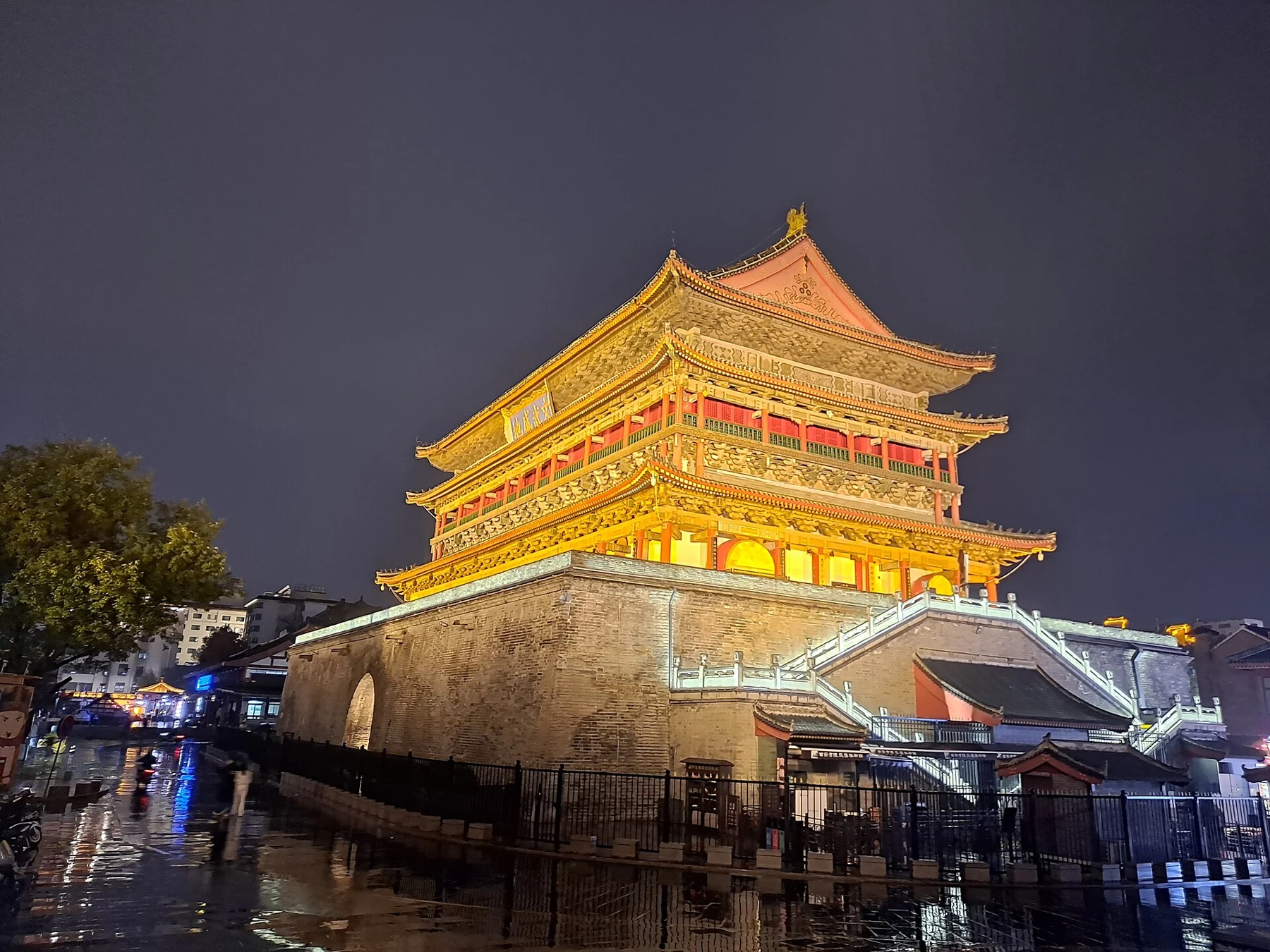 Illuminated Drum Tower and entrance stairways in a night street scene.