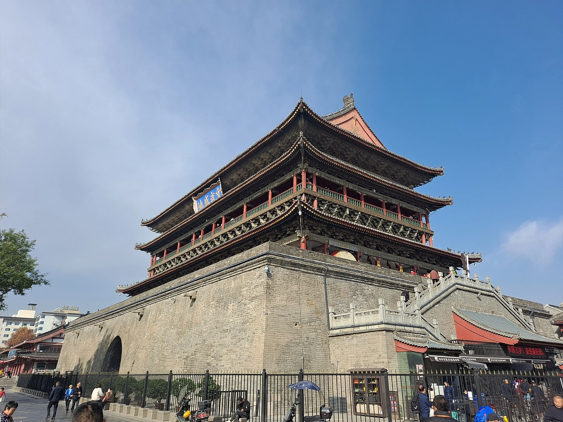 Drum Tower roof and masonry base seen obliquely from a pedestrian approach.