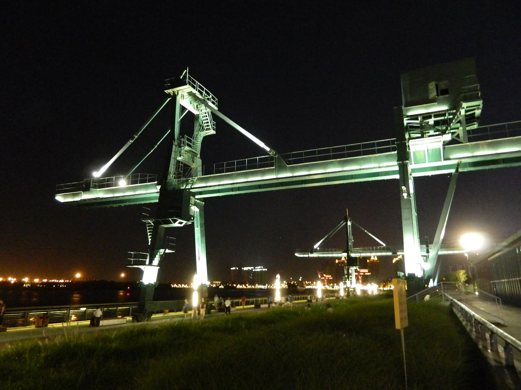Tall open steel gantry frames lit green against the night sky.