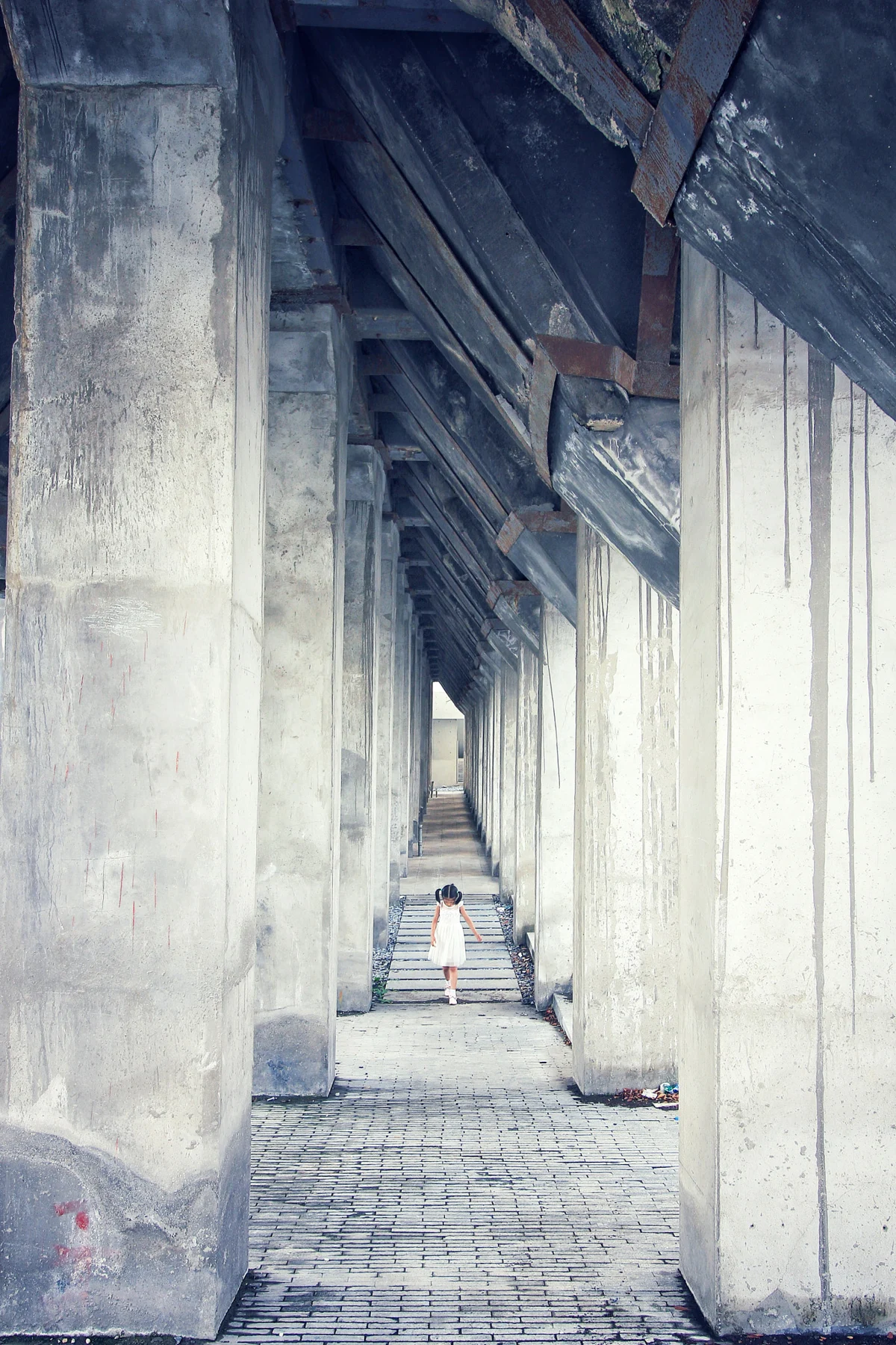 A person in a narrow passage between tall textured concrete supports.
