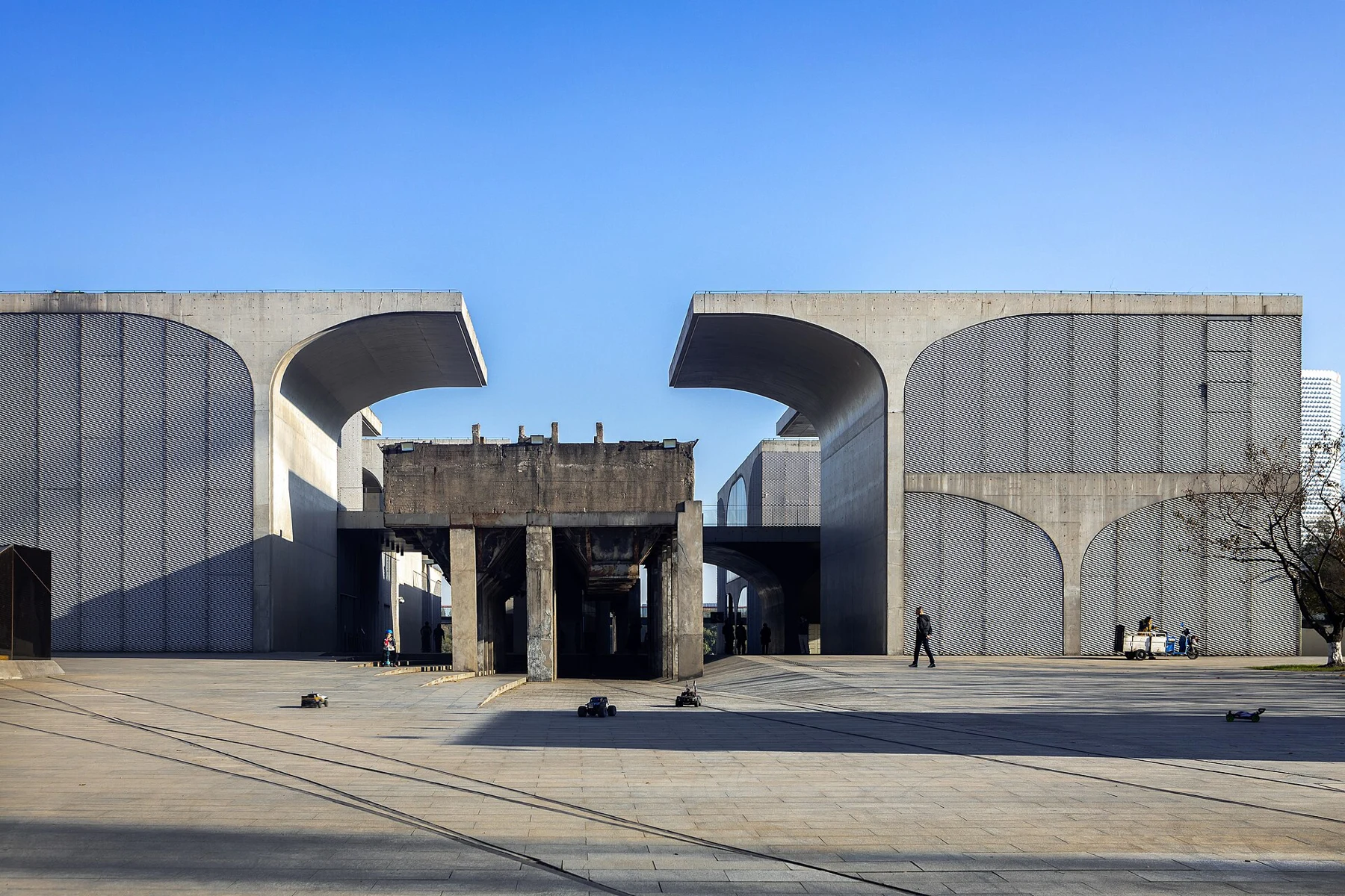 An old elevated industrial hopper framed by pale concrete museum vaults.
