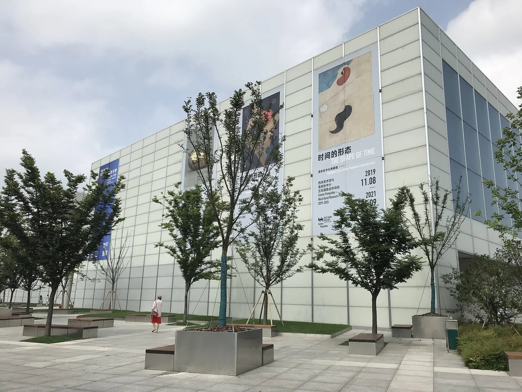 Glass-panelled museum volumes beside a broad paved area.