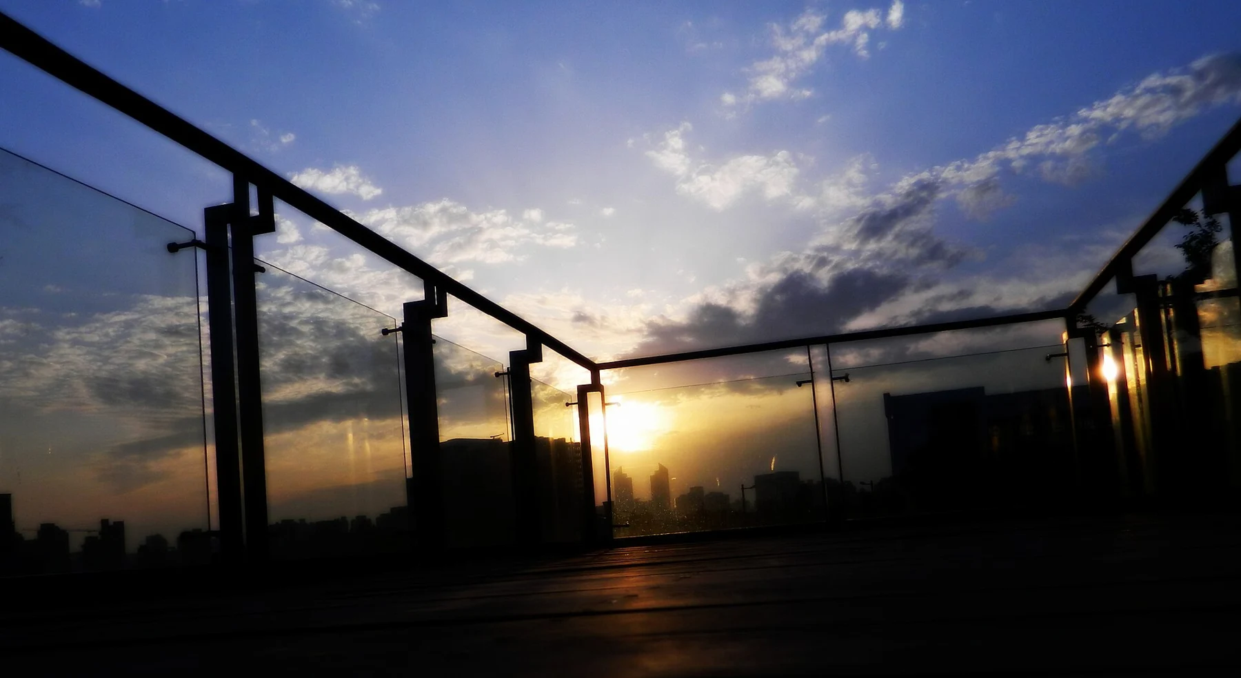 A glass-railed elevated platform above a darkening riverfront landscape.