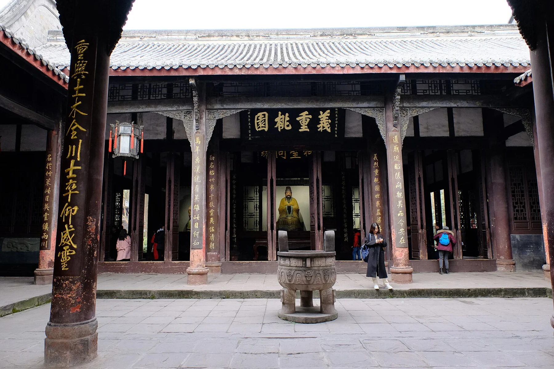 Sanyi Temple hall with a yellow-robed seated figure and the Yi Zhong Tao Yuan plaque