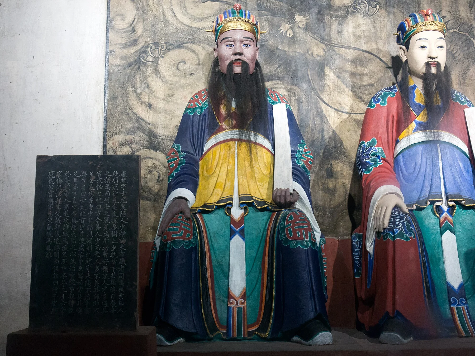 Two seated civil figures with robes and an identification panel