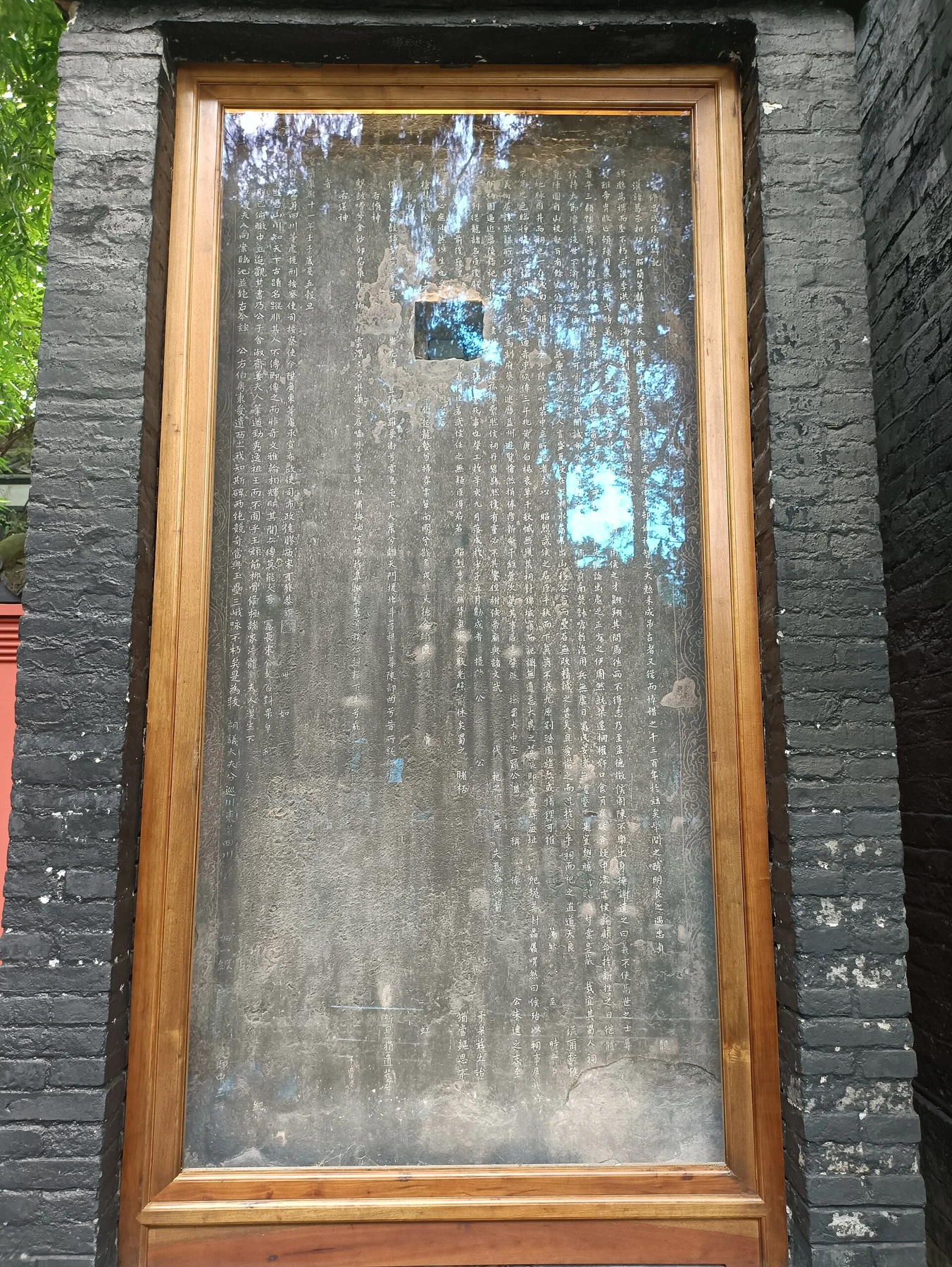 Tall inscribed stone slab in a protective frame