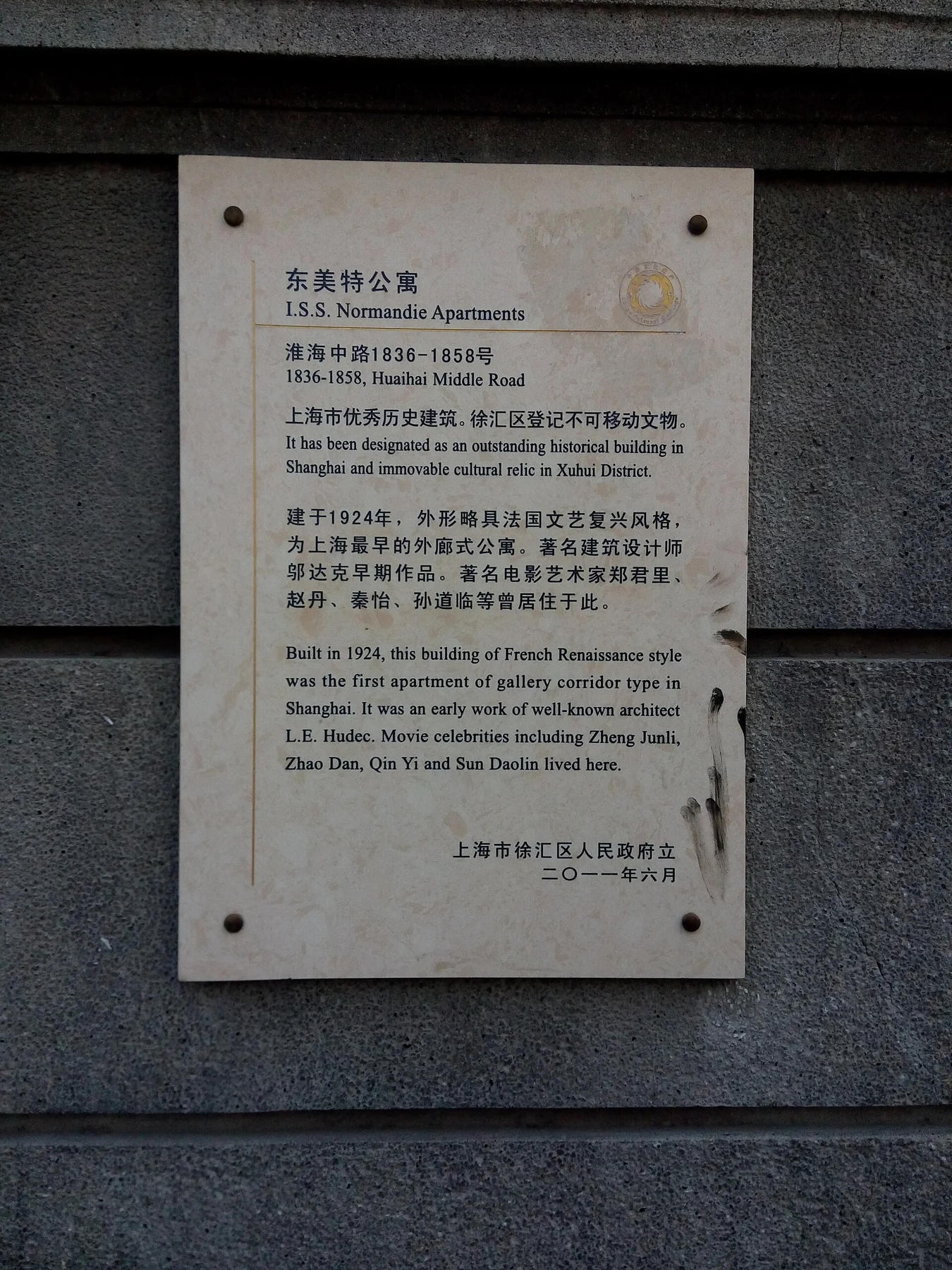 A rectangular heritage plaque fixed to a grey masonry wall.