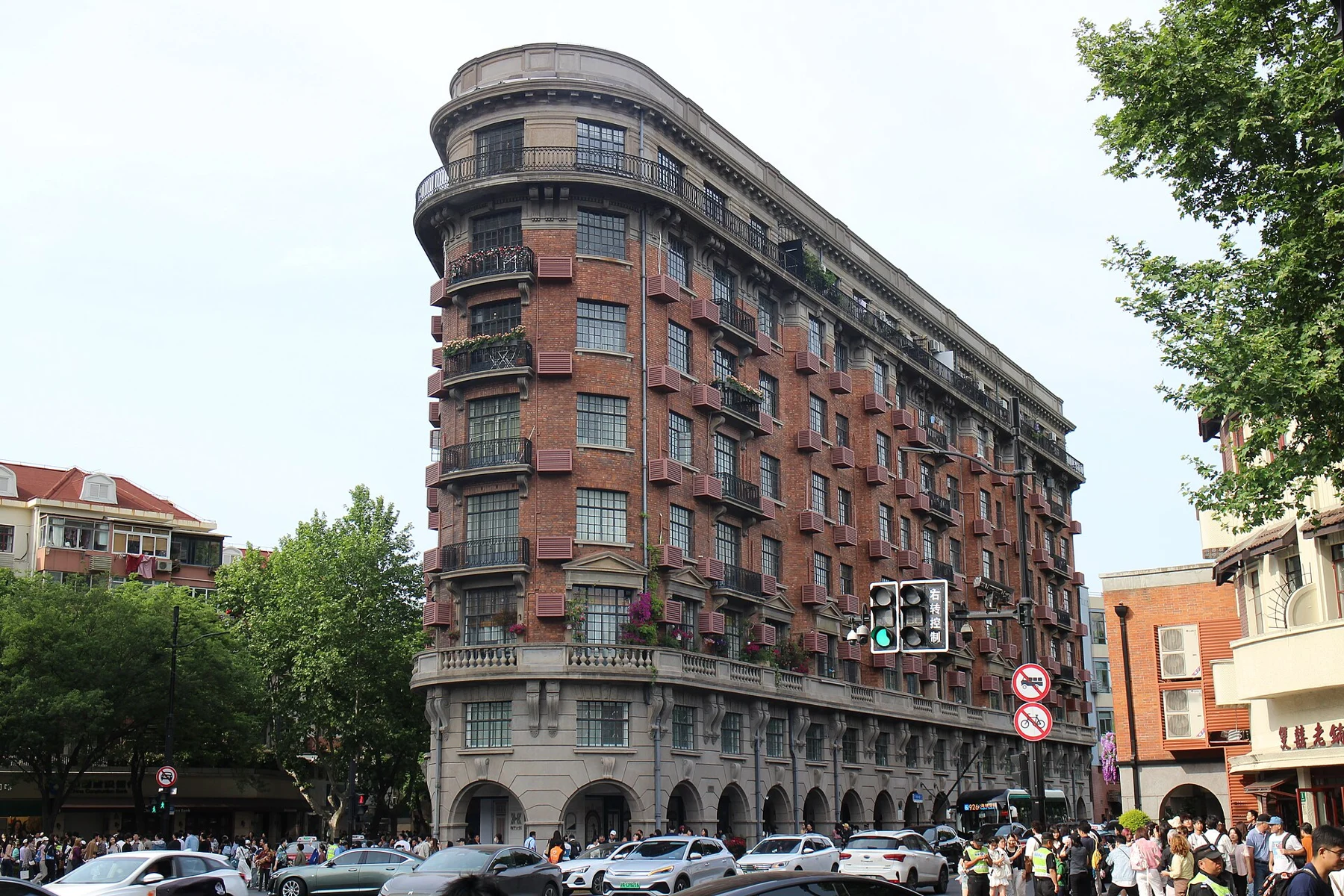 Red-brick balconies and repeating ground-floor arches along Wukang Building’s long frontage.