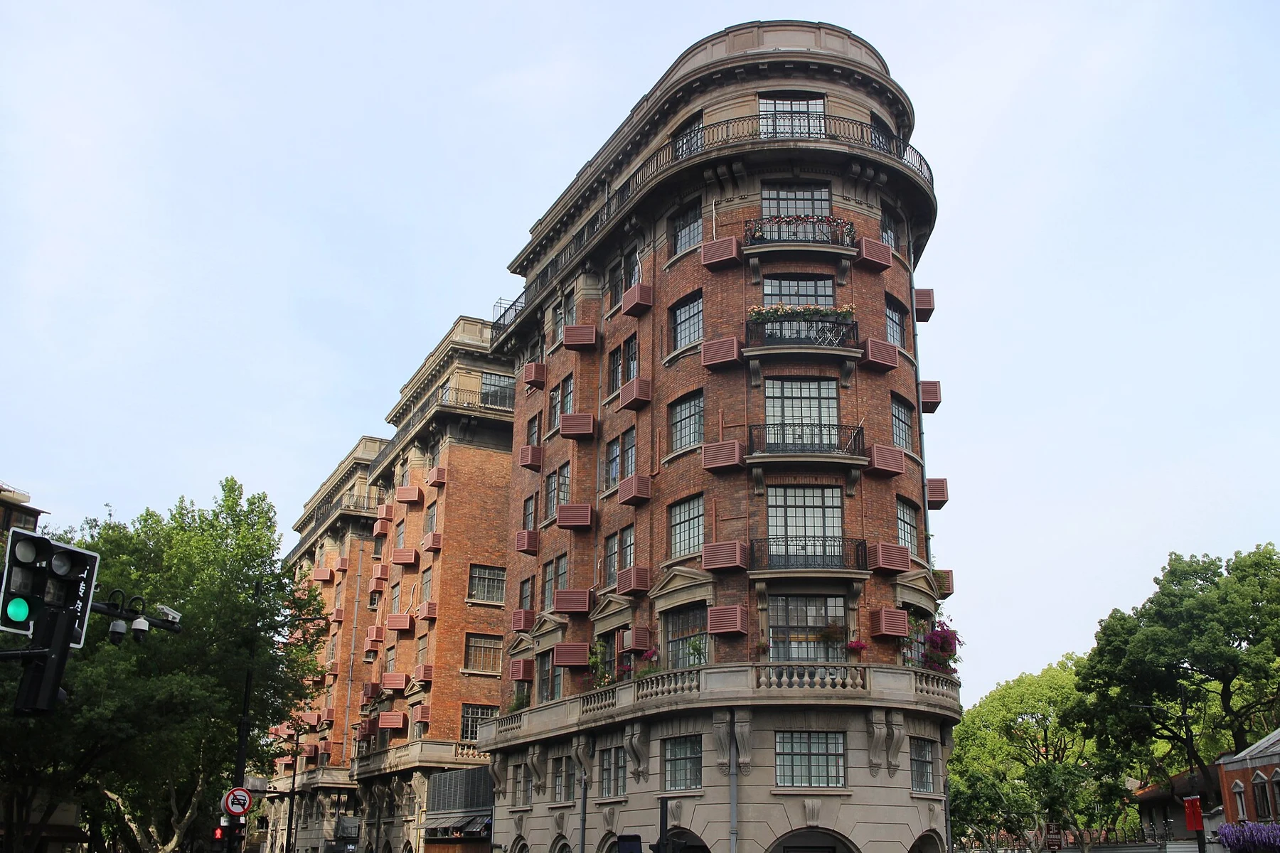 The rounded tip of a tall red-brick apartment building above a pale arched base.