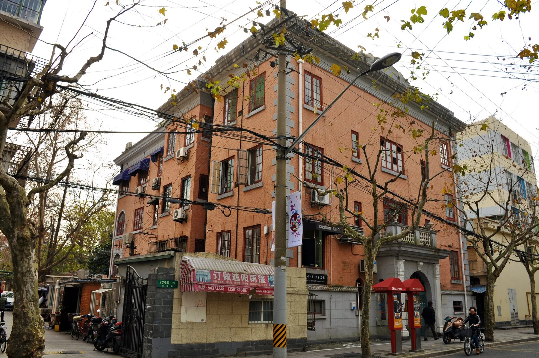 A peach-coloured corner apartment building with balconies and ground-floor shopfronts.