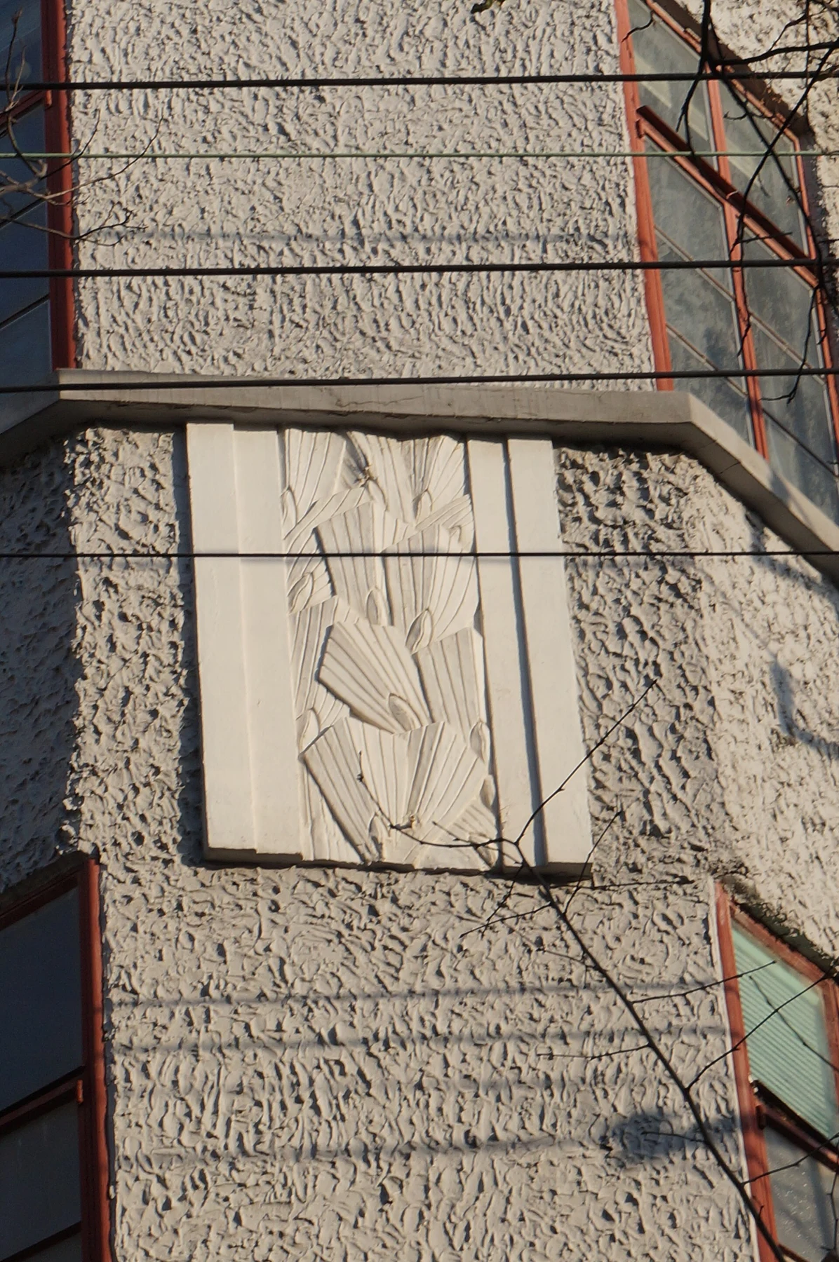 A shallow carved relief panel set into textured masonry on the apartment façade.