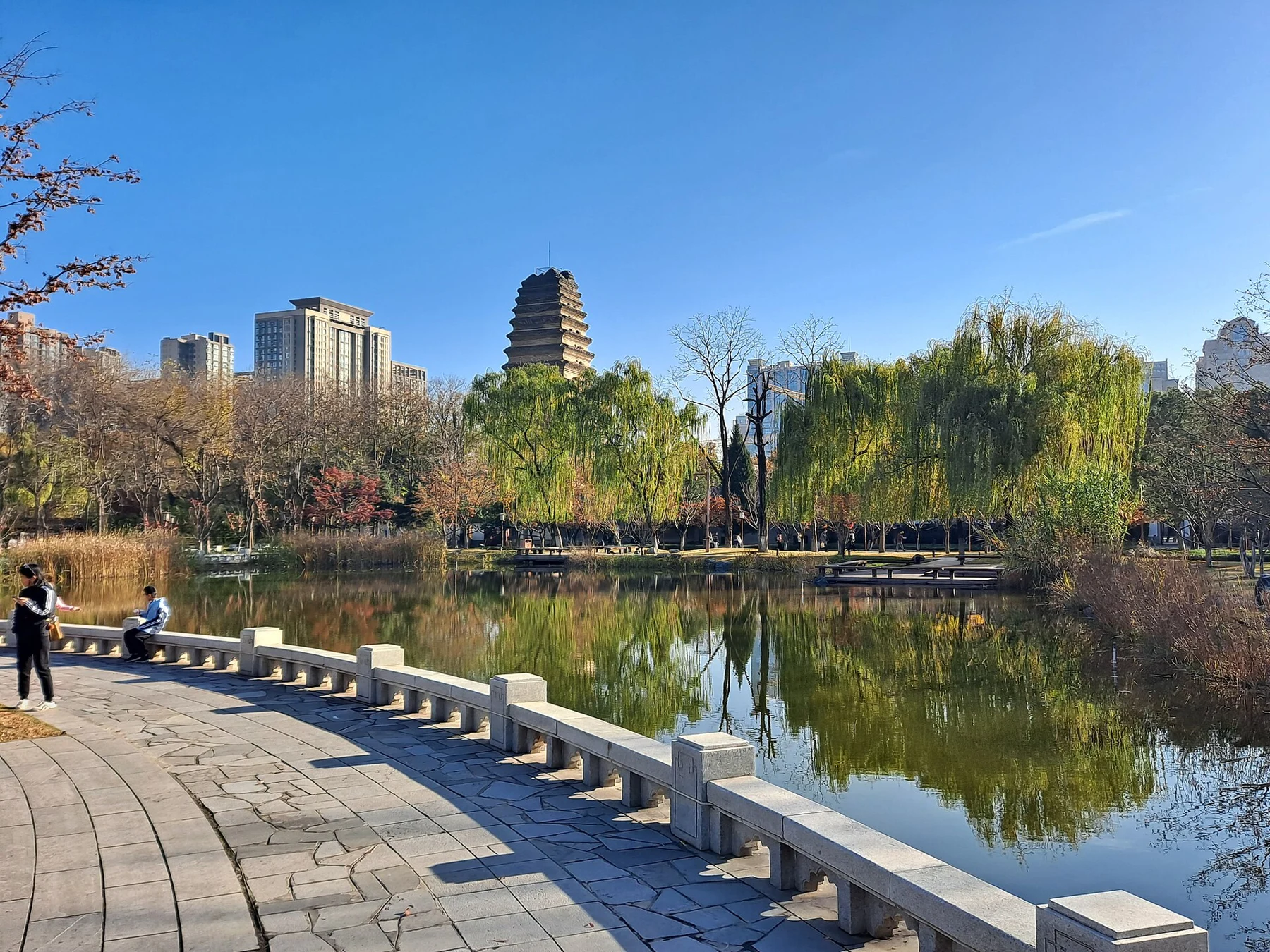 A curved lakeside path and trees with Small Wild Goose Pagoda beyond the water.