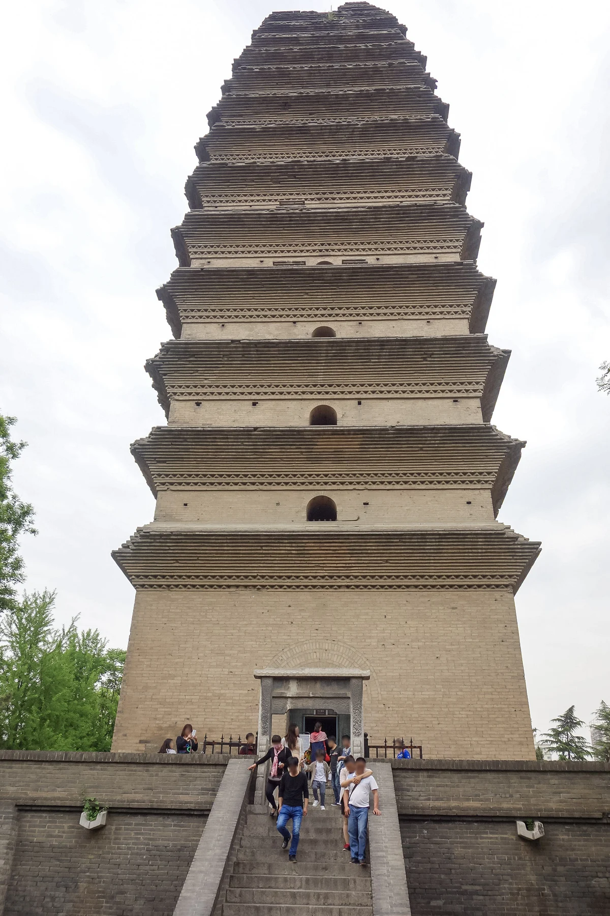 The narrowing brick tower with close projecting eaves and visitors on the historical approach steps.