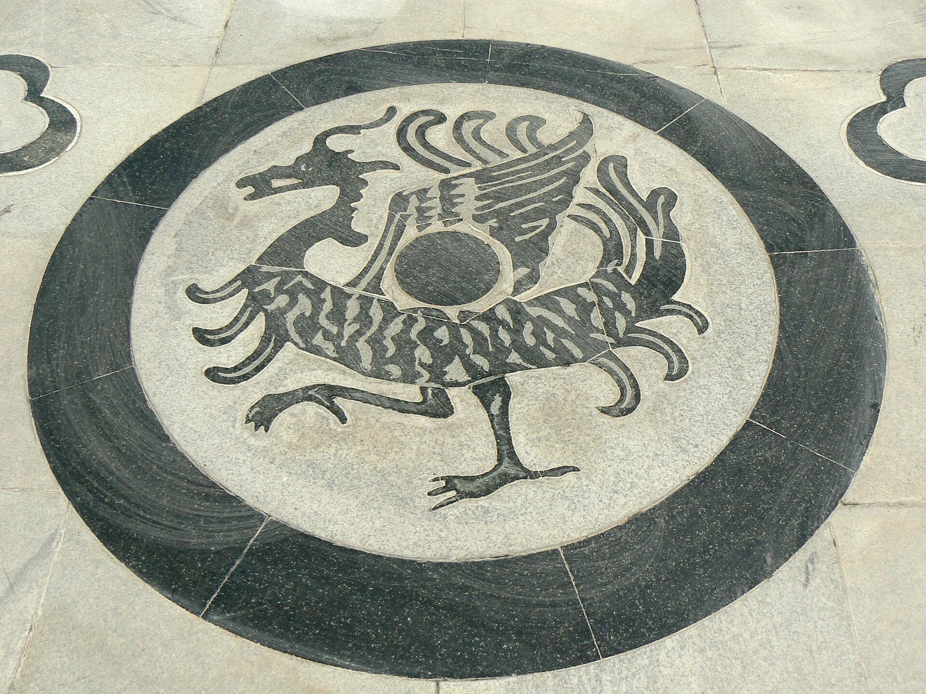 A circular dragon design made from contrasting paving stones.