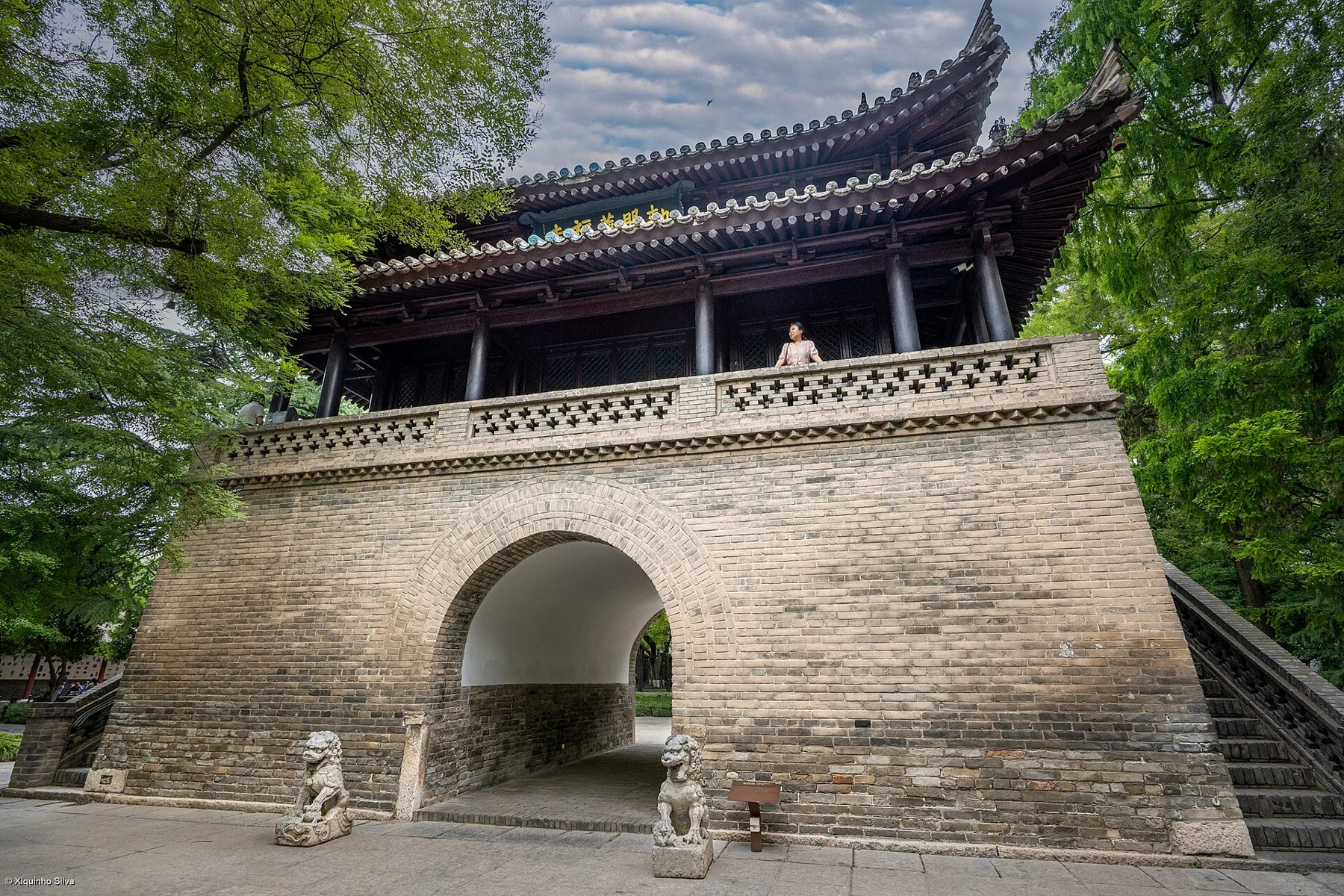 A raised pavilion at Jianfu Temple, with an arched passage through the brick base and an open timber gallery above.