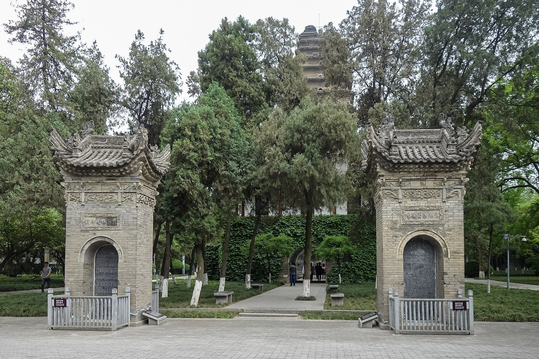 Two stone gateways on a tree-lined approach, with the pagoda visible behind them.
