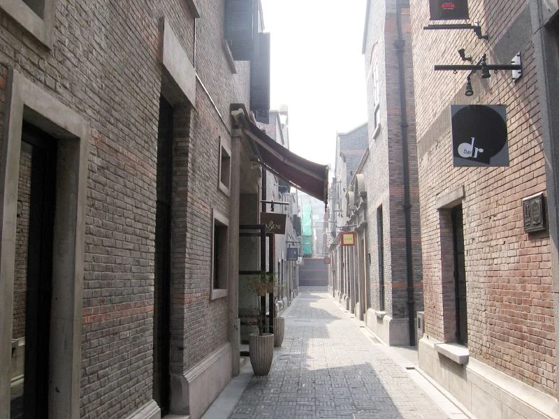 A narrow pedestrian passage between low brick buildings with projecting shop signs.