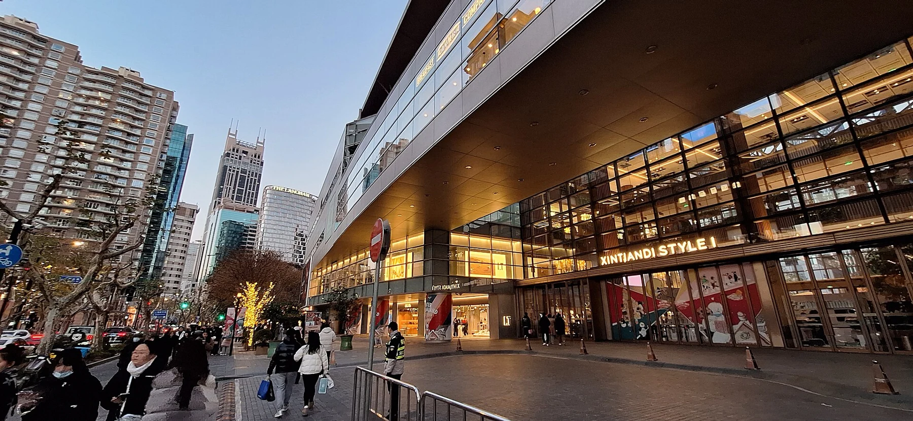 A long glazed contemporary shopping-centre frontage beside a busy pedestrian street.