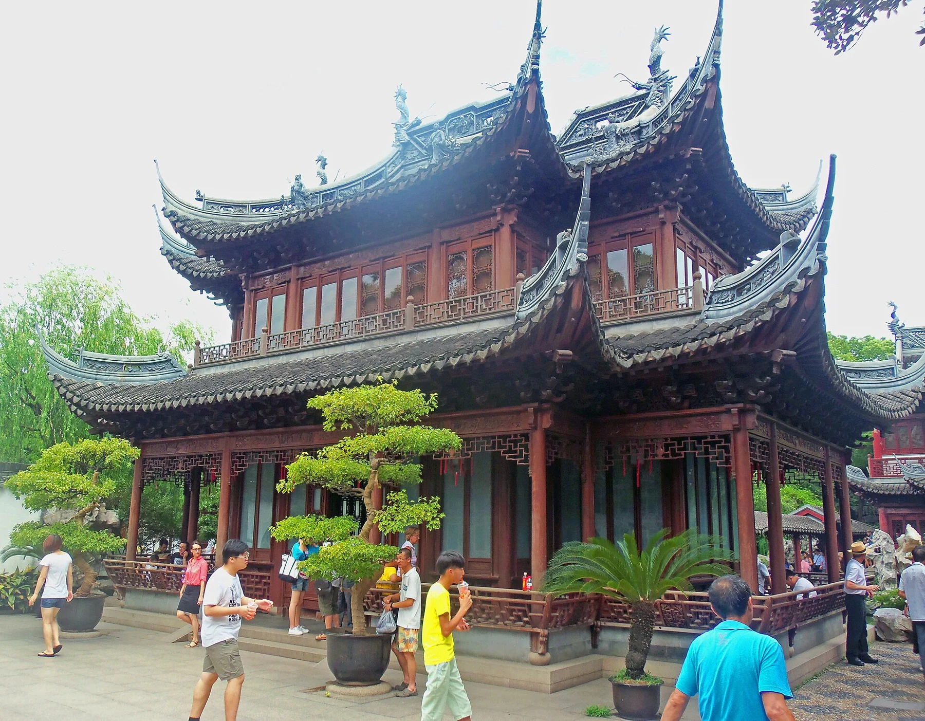 A garden timber building with carved architectural details beside the pond.