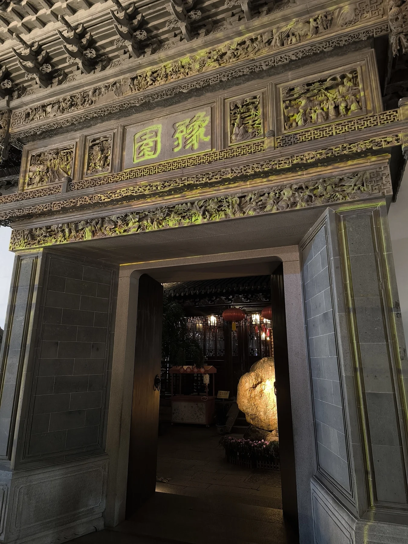 A close view of a carved stone doorway with the garden name above the opening and a rock visible beyond it.