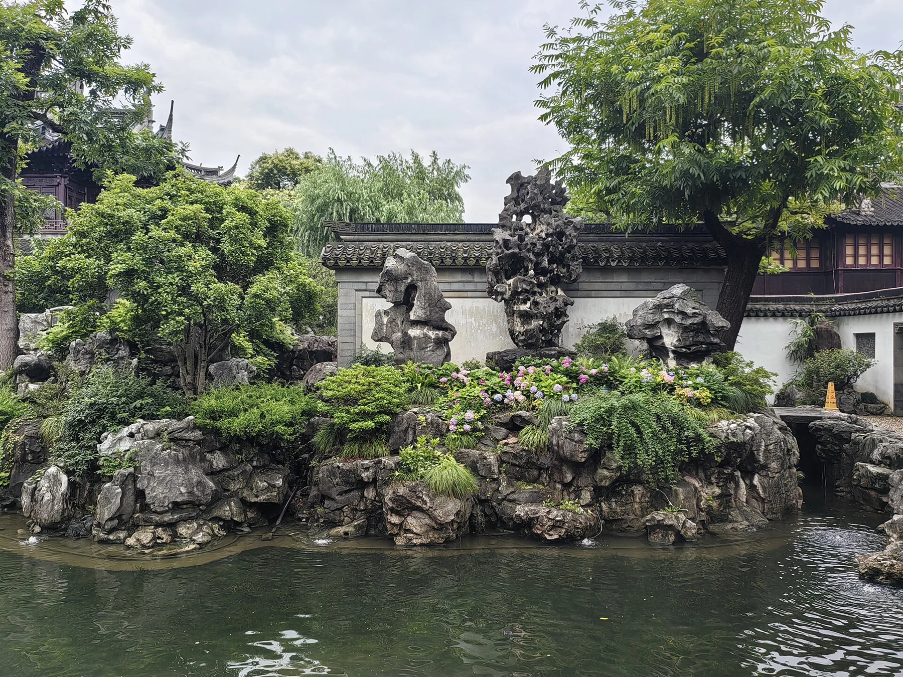 The dark pierced central rock and smaller flanking rocks reflected in a green pond.
