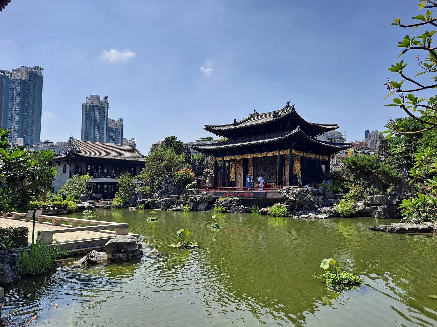Museum garden water with rocks, planting and a large tiled-roof pavilion.