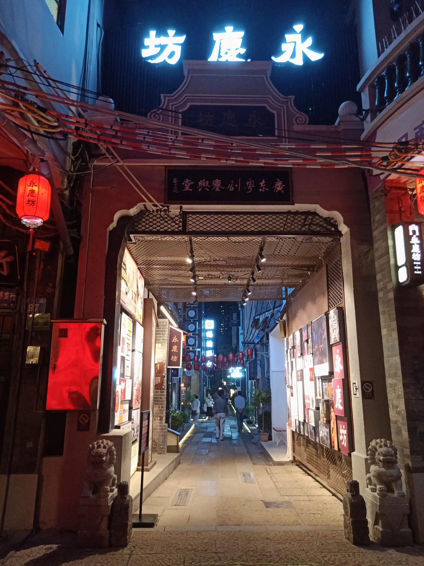 Yongqing Fang gateway illuminated at night with a narrow lane beyond.