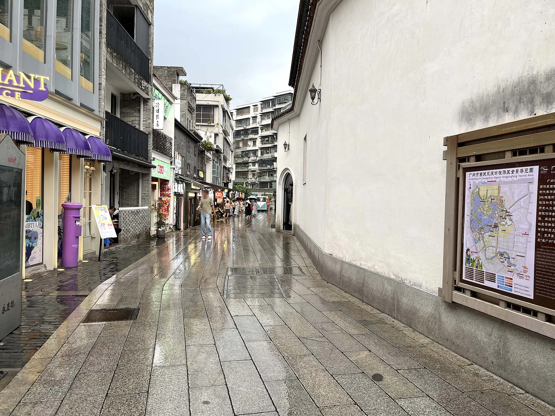 Wet Zhibao Dajie lane with building fronts and a wall-mounted information board.