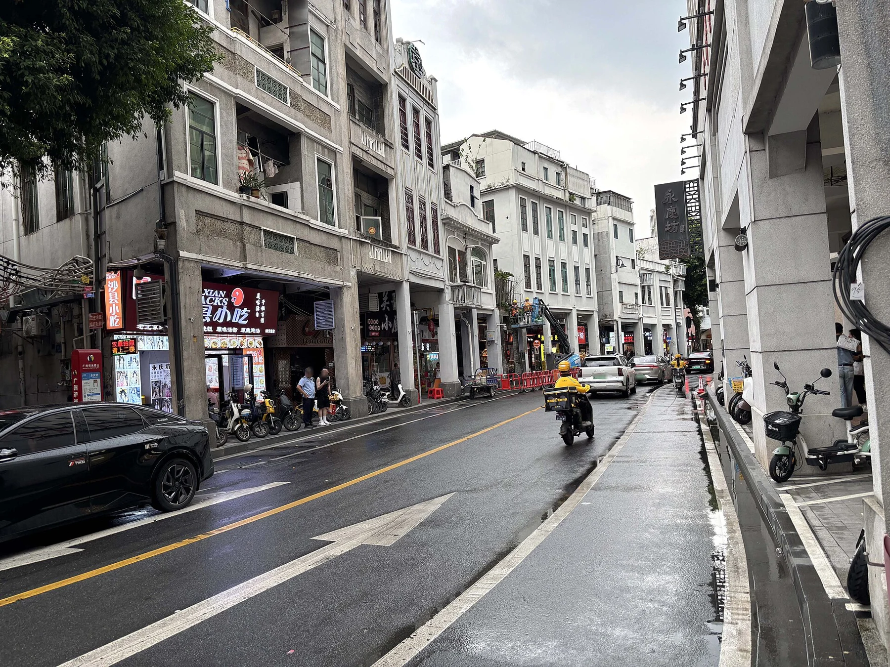 Wet Enning Road with arcade buildings, vehicles and a pedestrian pavement.