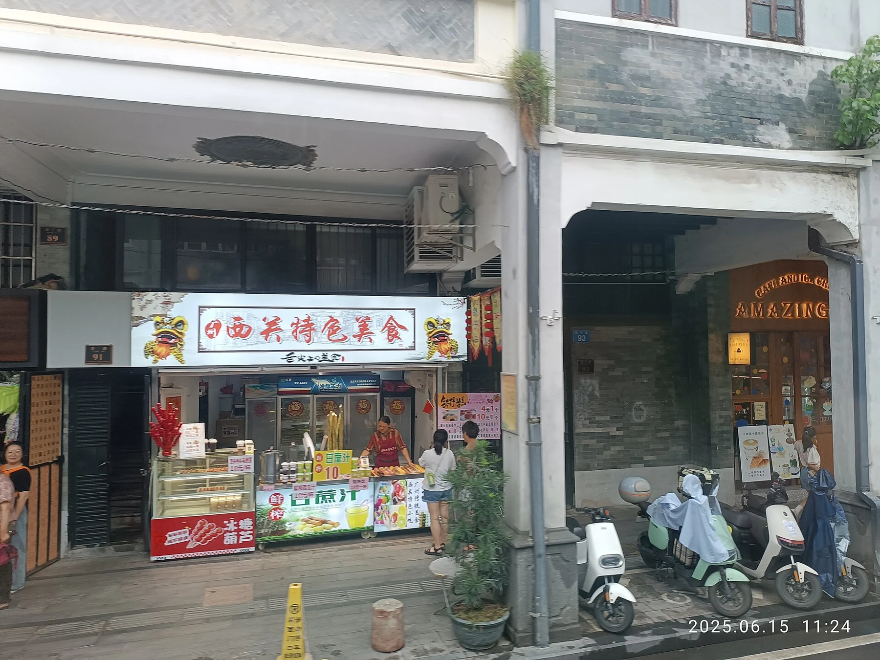 Street-level food and ice-cream shopfronts beneath older building fronts, with parked scooters.