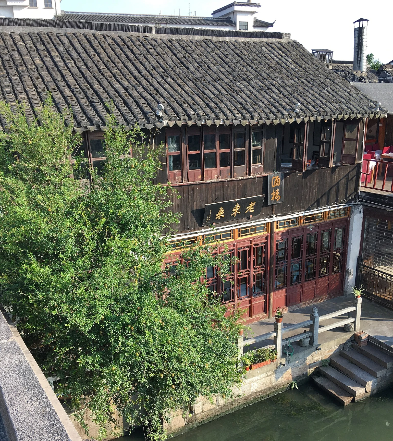 A timber-fronted tiled-roof building with small steps reaching down towards the water.